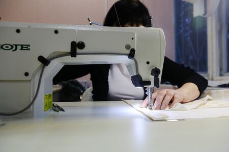 MINSK, BELARUS - February 25, 2020: former drug addict works as a seamstress on a sewing machineの写真素材