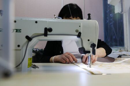 MINSK, BELARUS - February 25, 2020: former drug addict works as a seamstress on a sewing machineの写真素材