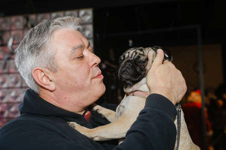 MINSK, BELARUS - February 25, 2020: the owner holds a beautiful pug in his armsのeditorial素材
