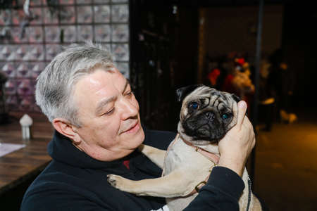 MINSK, BELARUS - February 25, 2020: the owner holds a beautiful pug in his armsのeditorial素材