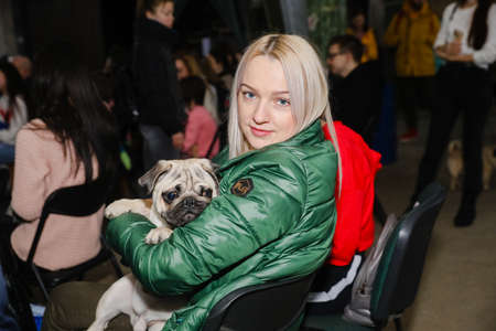 MINSK, BELARUS - February 25, 2020: the owner holds a beautiful pug in his armsのeditorial素材