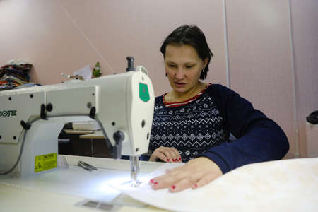 MINSK, BELARUS - February 25, 2020: former drug addict works as a seamstress on a sewing machineのeditorial素材