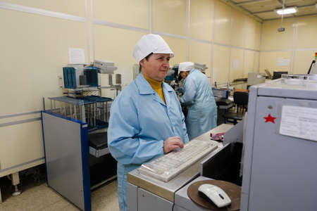 MINSK, BELARUS - February 25, 2020: Electronics Factory Worker a Printed Circuit Board Through a Digital Microscope High Tech Factory Facilityのeditorial素材