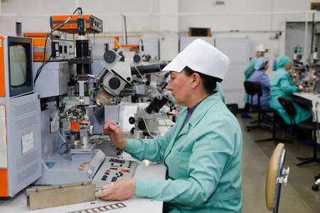 MINSK, BELARUS - February 25, 2020: Electronics Factory Worker a Printed Circuit Board Through a Digital Microscope High Tech Factory Facilityのeditorial素材