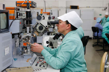 MINSK, BELARUS - February 25, 2020: Electronics Factory Worker a Printed Circuit Board Through a Digital Microscope High Tech Factory Facilityのeditorial素材