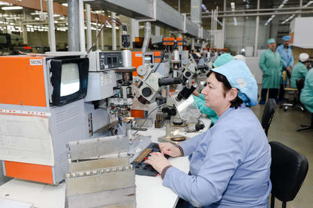 MINSK, BELARUS - February 25, 2020: Electronics Factory Worker a Printed Circuit Board Through a Digital Microscope High Tech Factory Facilityのeditorial素材