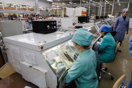MINSK, BELARUS - February 25, 2020: Electronics Factory Worker a Printed Circuit Board Through a Digital Microscope High Tech Factory Facilityのeditorial素材