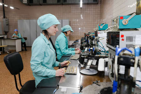 MINSK, BELARUS - February 25, 2020: Electronics Factory Worker a Printed Circuit Board Through a Digital Microscope High Tech Factory Facilityのeditorial素材