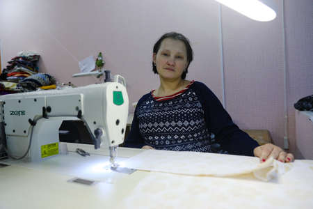 MINSK, BELARUS - February 25, 2020: former drug addict works as a seamstress on a sewing machineのeditorial素材