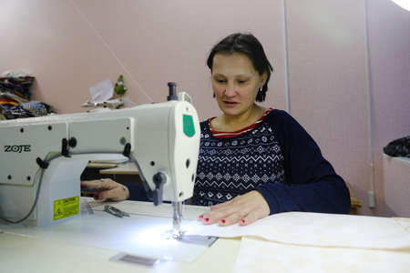 MINSK, BELARUS - February 25, 2020: former drug addict works as a seamstress on a sewing machineのeditorial素材