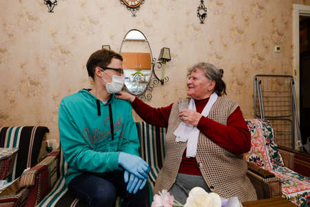 MINSK, BELARUS - February 25, 2020:  social worker volunteer helps old woman coronavirusのeditorial素材