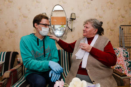 MINSK, BELARUS - February 25, 2020:  social worker volunteer helps old woman coronavirusのeditorial素材