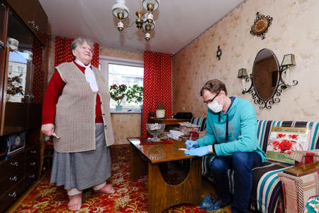 MINSK, BELARUS - February 25, 2020:  social worker volunteer helps old woman coronavirusのeditorial素材