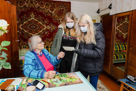 MINSK, BELARUS - February 25, 2020:  social worker volunteer helps old woman coronavirusのeditorial素材