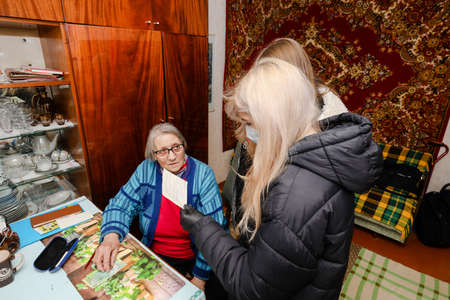 MINSK, BELARUS - February 25, 2020:  social worker volunteer helps old woman coronavirusのeditorial素材