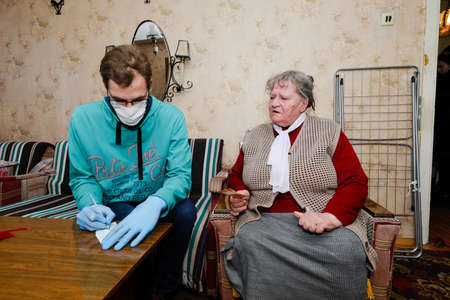 MINSK, BELARUS - February 25, 2020:  social worker volunteer helps old woman coronavirusのeditorial素材