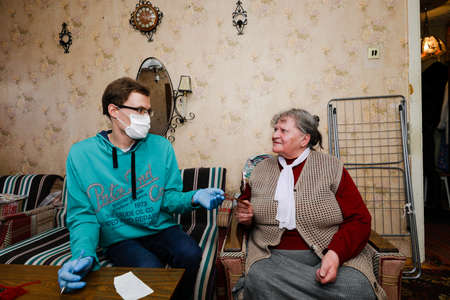 MINSK, BELARUS - February 25, 2020:  social worker volunteer helps old woman coronavirusのeditorial素材