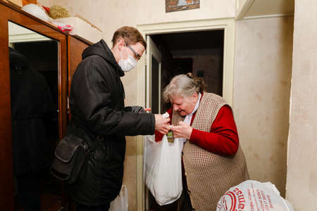 MINSK, BELARUS - February 25, 2020:  social worker volunteer helps old woman coronavirusのeditorial素材