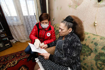 MINSK, BELARUS - 1 MARCH, 2020: red cross volunteer helps an elderly person during coronavirusのeditorial素材