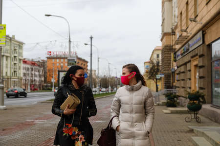 MINSK, BELARUS - 1 MARCH, 2020: two womans in protective masks from coronavirus walk along the city streetのeditorial素材