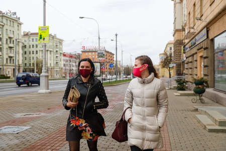 MINSK, BELARUS - 1 MARCH, 2020: two womans in protective masks from coronavirus walk along the city streetのeditorial素材