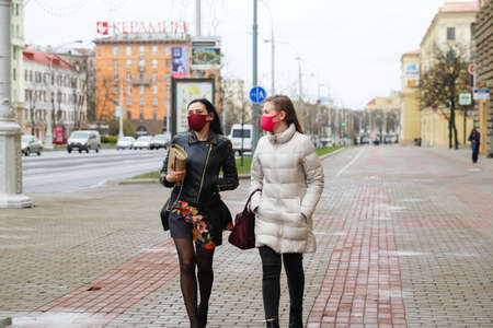 MINSK, BELARUS - 1 MARCH, 2020: two womans in protective masks from coronavirus walk along the city streetのeditorial素材