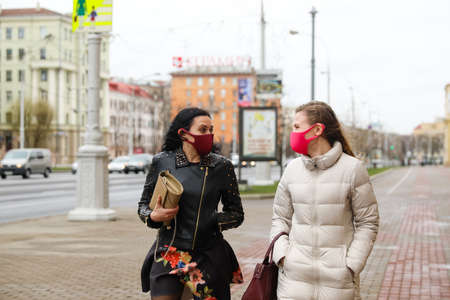 MINSK, BELARUS - 1 MARCH, 2020: two womans in protective masks from coronavirus walk along the city streetのeditorial素材