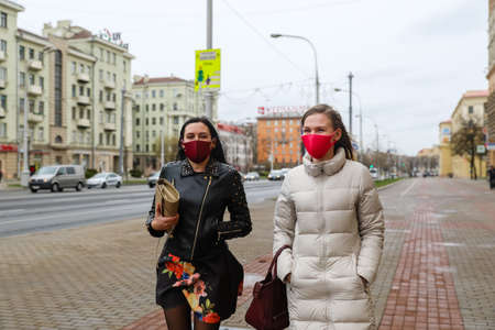 MINSK, BELARUS - 1 MARCH, 2020: two womans in protective masks from coronavirus walk along the city streetのeditorial素材