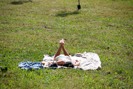 MINSK, BELARUS - 9 AUGUST, 2020: people sunbathe in the city park in sunny hot weather