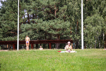 MINSK, BELARUS - 9 AUGUST, 2020: people sunbathe in the city park in sunny hot weatherの写真素材