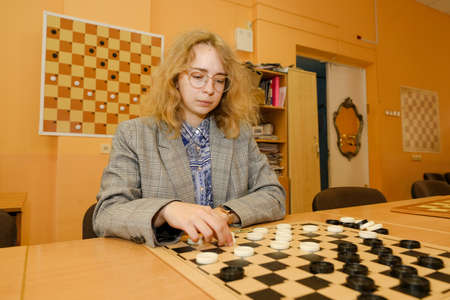 MINSK, BELARUS - 18 FEBRUARY, 2022: young girl playing checkersのeditorial素材