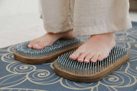 MINSK, BELARUS - 22 July, 2022: Practice of standing on nails woman puts his foot on a board with nailsの写真素材
