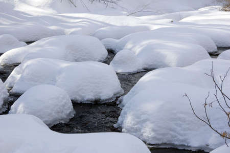 Snowy creek with snow bumpsの写真素材