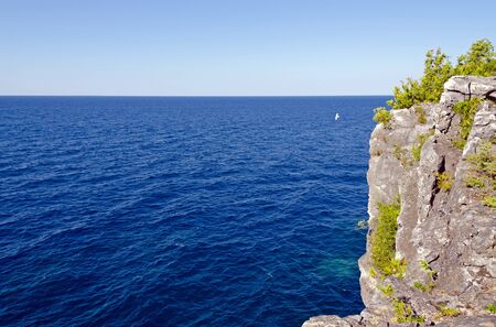 Green and blue water of Huron Lake, Ontario under blue sky.