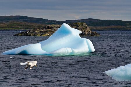 Bright white iceberg on dark water and rock backgroundの写真素材