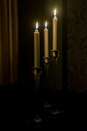 Three candles light in the darkness and black roomの写真素材