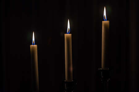Three candles light in the darkness and black roomの写真素材