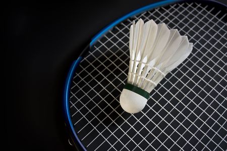 Shuttlecock over racket isolated on the black backgroundの写真素材