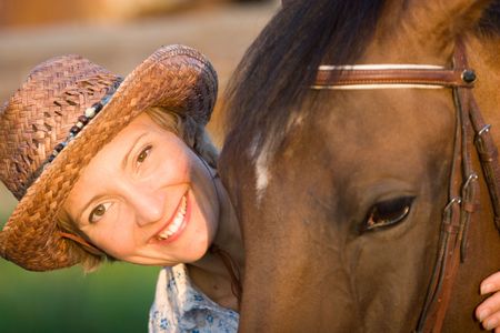 Woman in hat embrace brown horse. Close-up portrateの写真素材