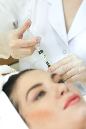 Hand with a syringe over the face, close up. Focus on syringeの写真素材