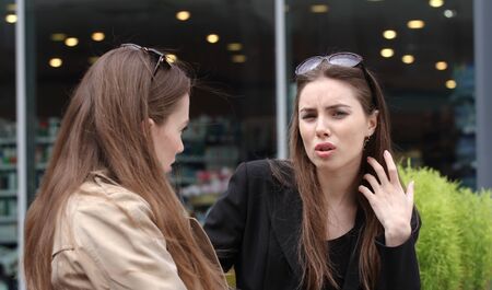 Two girls talking on the bench in front of business Ñentre