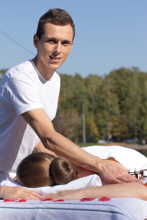 Man giving massage to young brunette outdoors sunny dayの写真素材