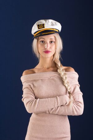 Sexy blonde with long hair in a beautiful dress and captain's capの写真素材