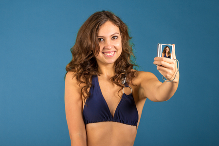 happy young woman in bikini swimsuit and camera on blue backgroundの写真素材