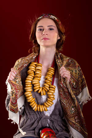 Portrait of young woman in Rissian dress, national scarf on red backgeroundの写真素材