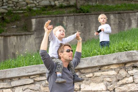 Blond boy sitting on fathers shoulder outdoors