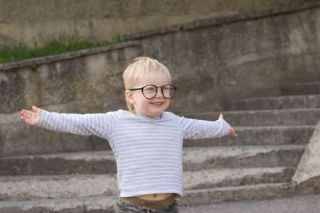 Happy child with falling down glasses, outdoorsの写真素材