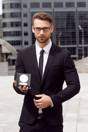 Happy Businessman with award on urban background