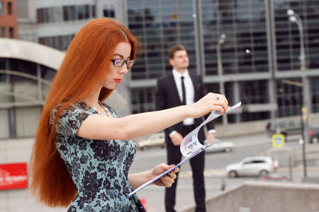 Ginger woman posing on jumping businessman backgroundの写真素材