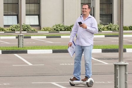 Business man riding an electronic scooter outdoors - personal portable eco transport, hover board, gyro scooter, hyroscooter, smart balance wheelの写真素材